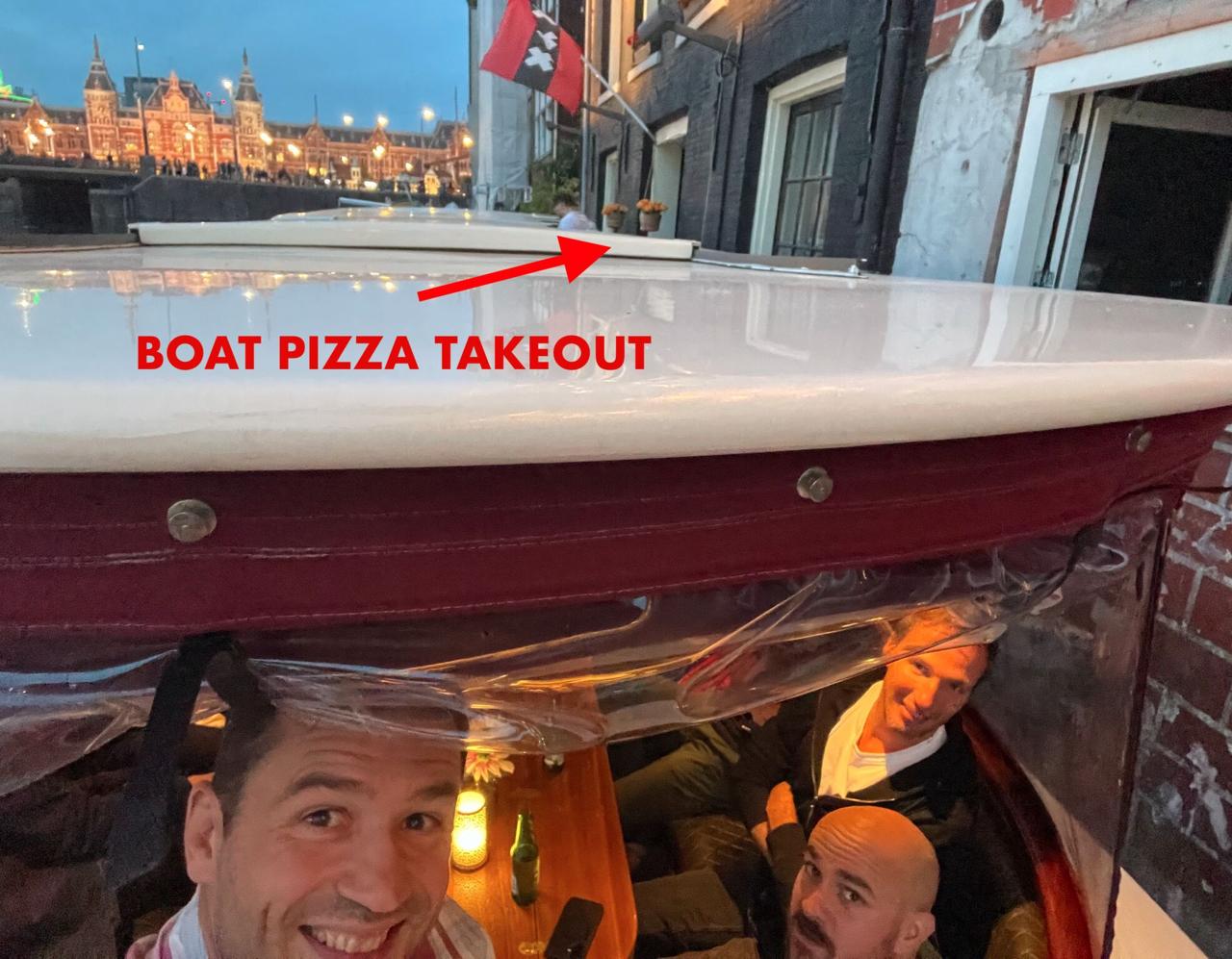 BOAT PIZZA TAKEOUT - group selfie on the canal boat with Amsterdam Centraal in the background