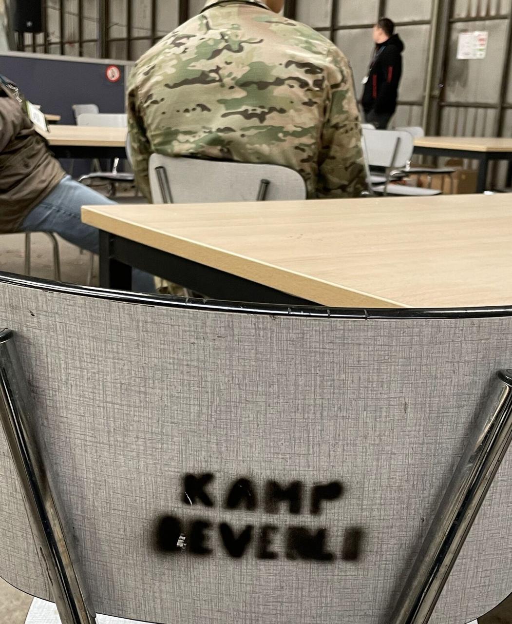 Back of a chair at Vlasmeer FOB with KAMP BEVELEN written on it in black marker - army surplus furniture