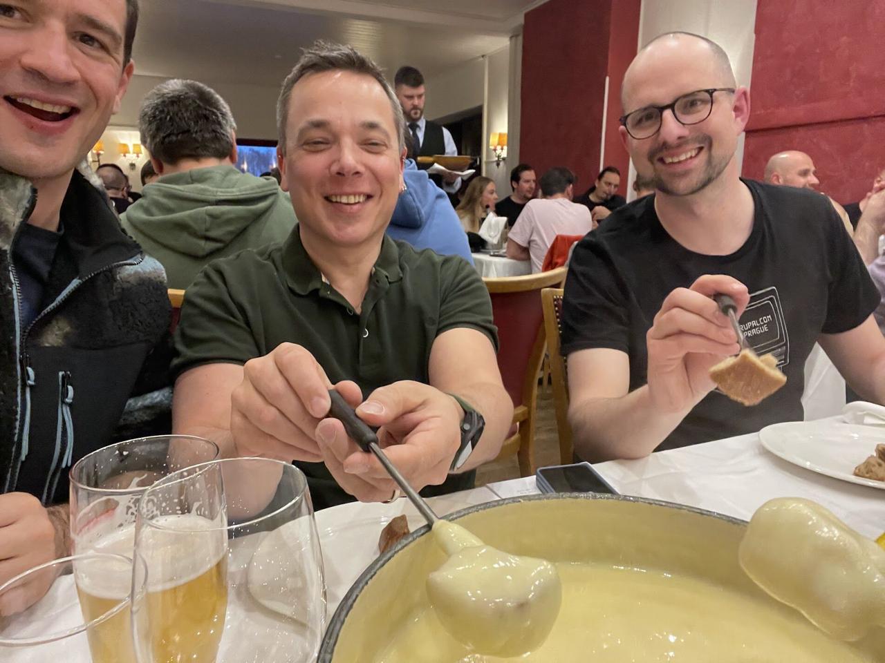Three people at a fondue dinner, smiling and dipping bread