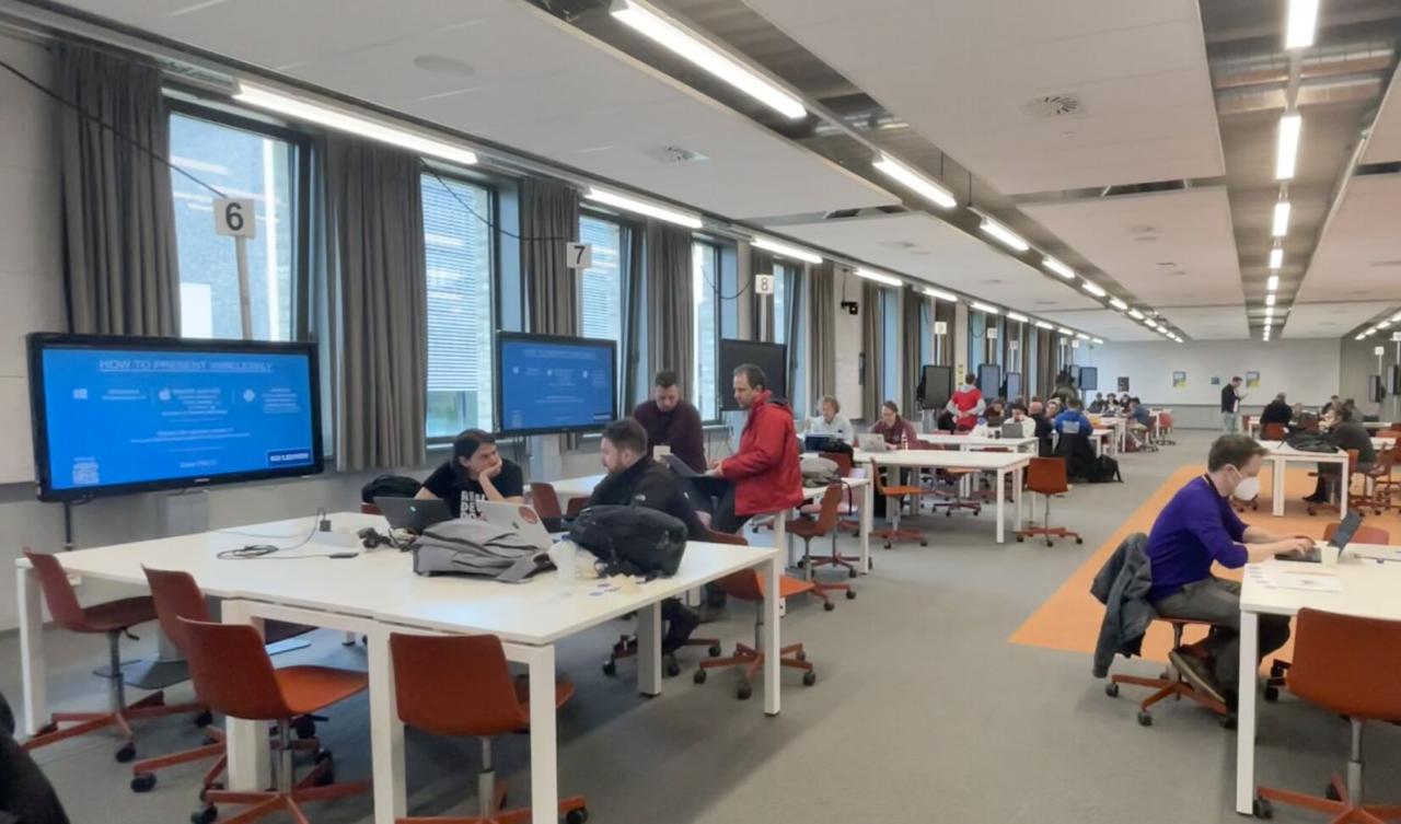The contribution room - long rows of tables with attendees working on laptops