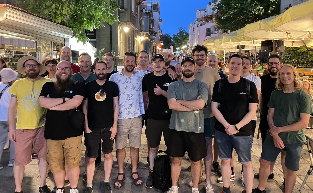 Large group of Drupal conference attendees on a Bulgarian city street at night, smiling for the camera