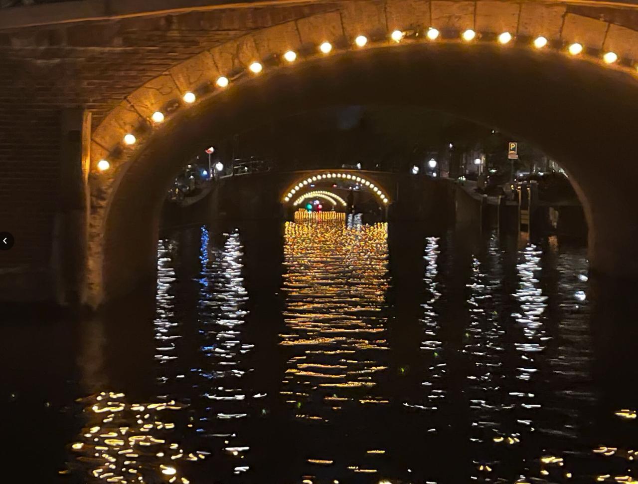 Amsterdam canal at night, lights reflecting on the water under a bridge arch