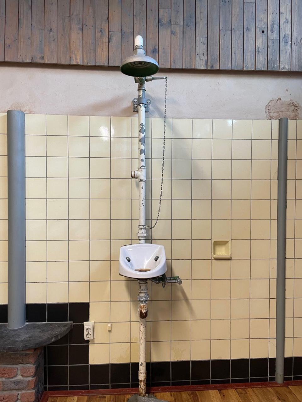 Original industrial eye-shower fixture in the old soap factory, mounted on tiled wall - old factory safety equipment