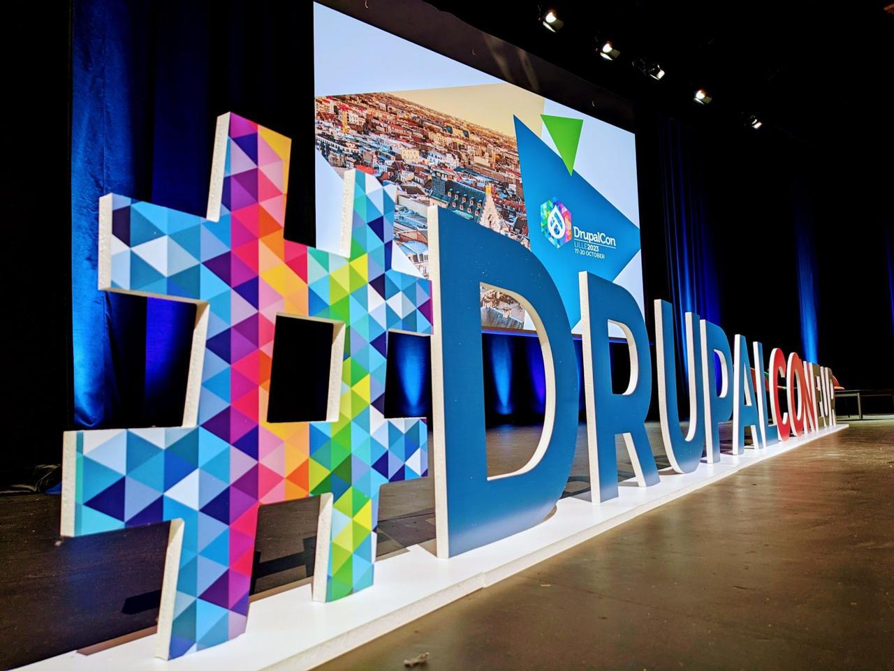 Giant #DRUPALCON letters on stage at Lille Grand Palais with DrupalCon Lille 2023 17-20 October branding