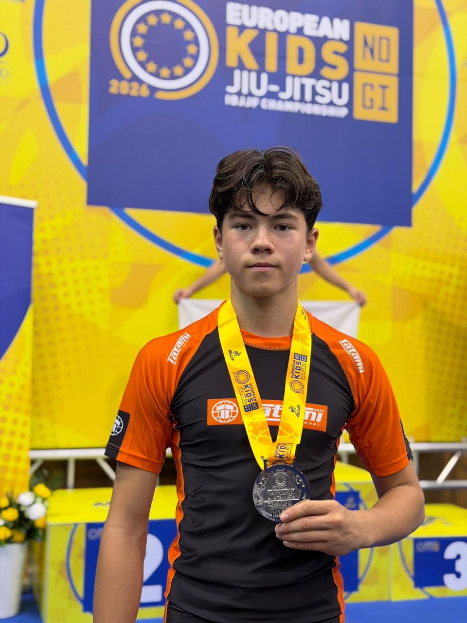 Jules op het podium van het IBJJF European Kids No-Gi Championship 2026 in Lissabon, met een zilveren medaille