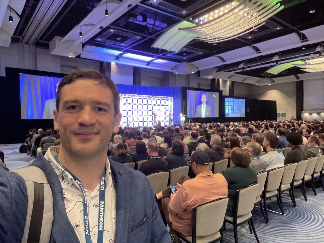 Frederik selfie at the DrupalCon keynote with a packed auditorium and speaker on stage behind him