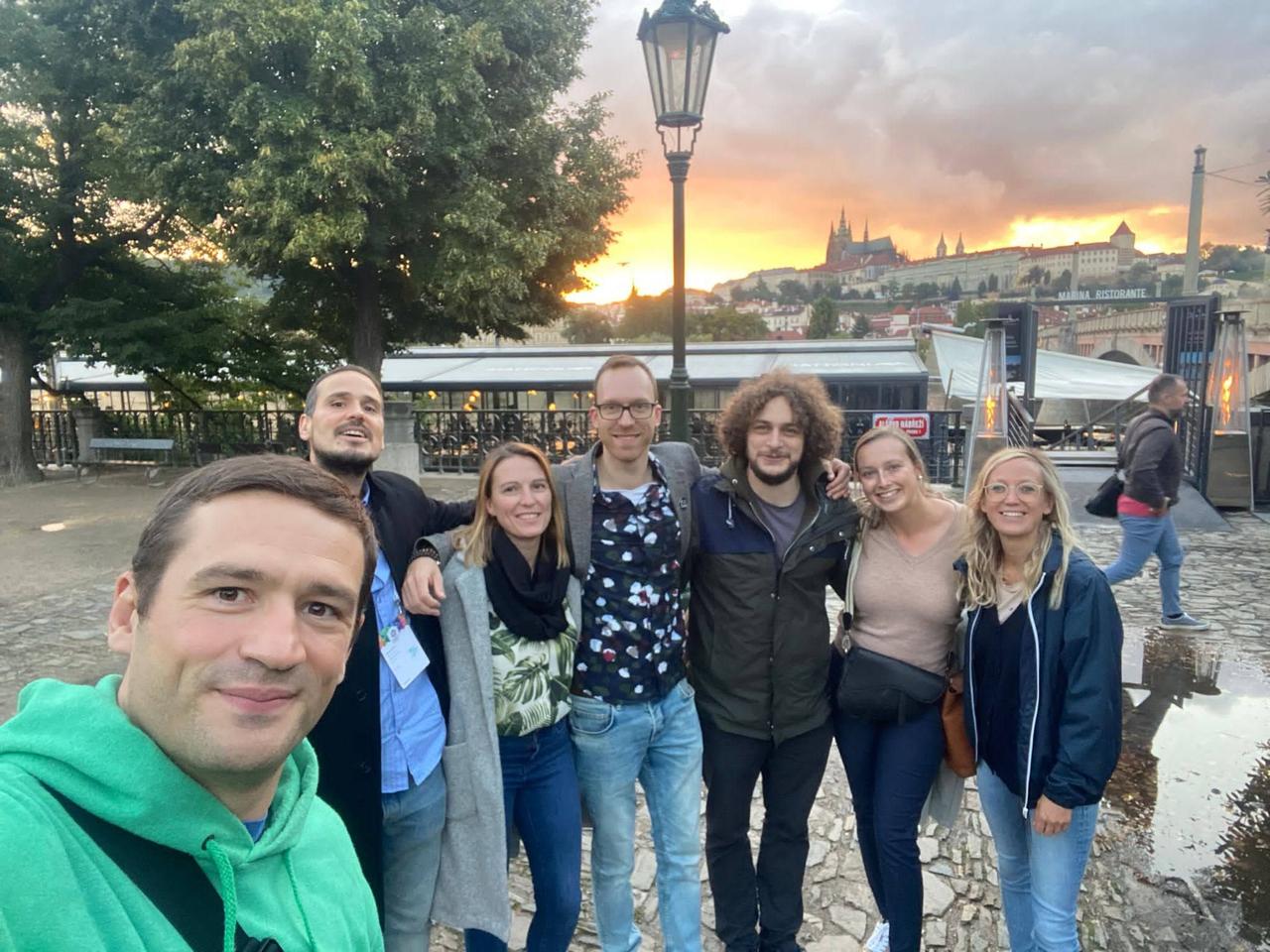 DrupalCon Prague 2022 - Dropsolid group selfie in front of Prague Castle at sunset, six people smiling
