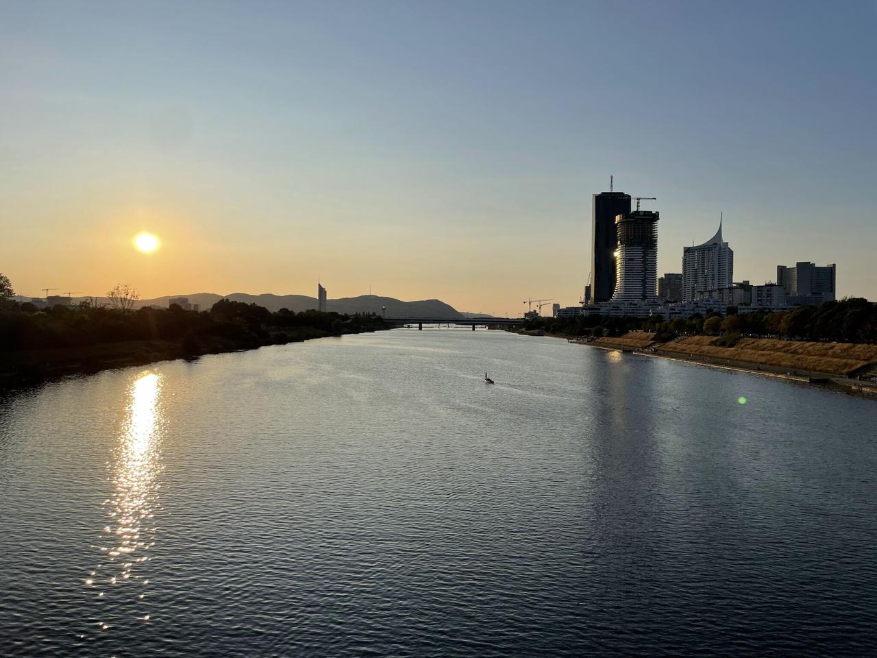Vienna skyline at sunset from the Danube - DC Tower and other towers reflected in the calm water