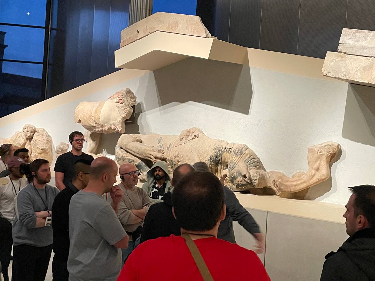 Group of Drupalists gathered in front of a large marble pediment sculpture at the Parthenon Museum