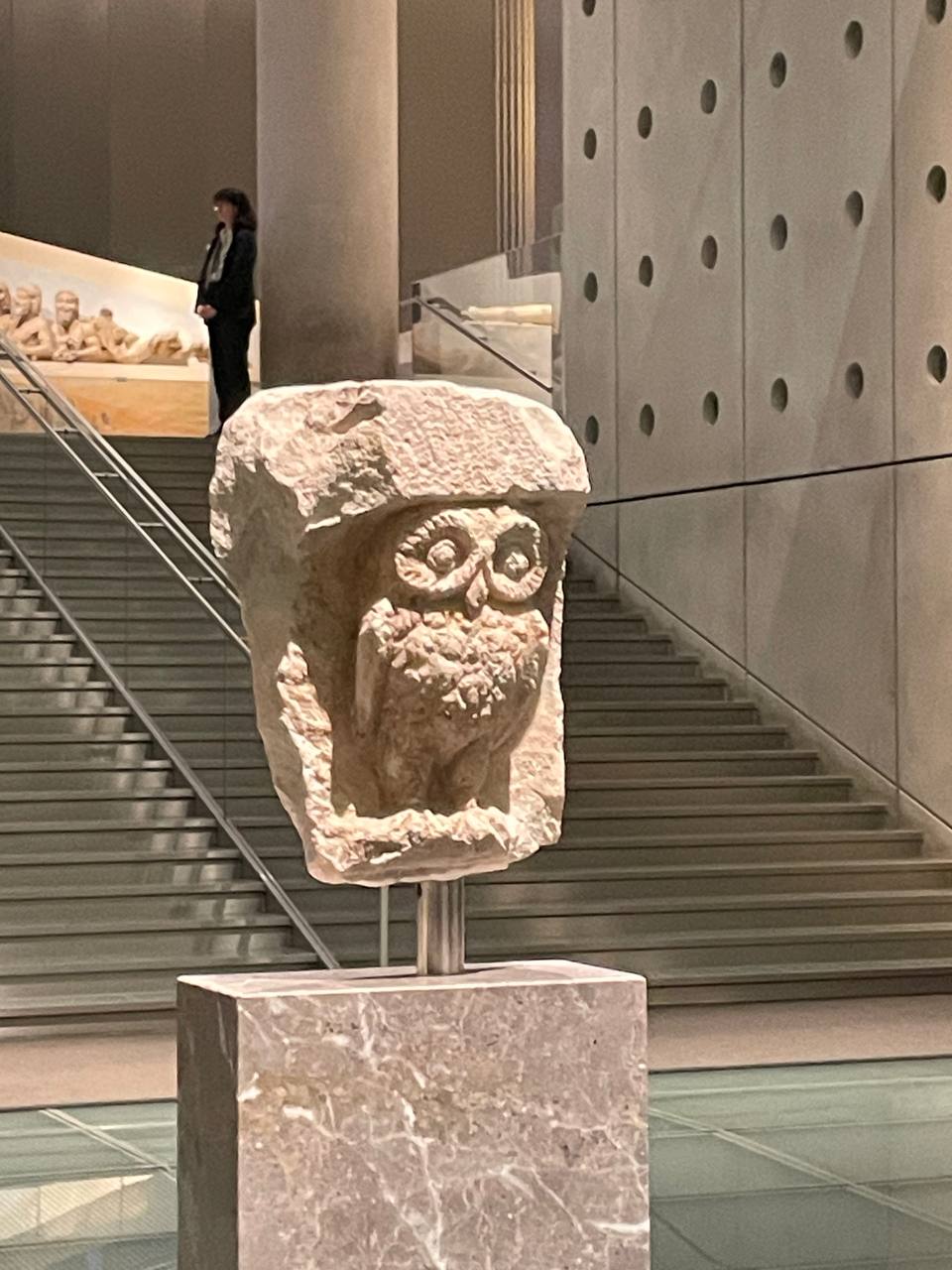 Ancient Greek stone carving of an owl, symbol of Athena, displayed on a pedestal in the Parthenon Museum in Athens